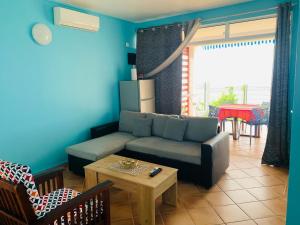 a living room with a couch and a table at PARADIS AU SOLEIL, vue panoramique sur mer in Bouillante