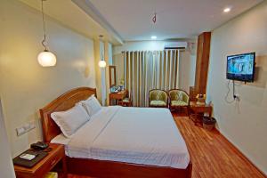 una camera d'albergo con un letto e una televisione di Royal Pearl Hotel a Mandalay