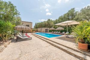 a swimming pool with umbrellas and lounge chairs next to a house at Finca Es Rafalot de Dalt by Mallorca House Rent in Manacor
