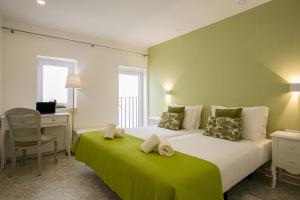 1 dormitorio con 1 cama grande con manta verde en Suites Amália Guesthouse near Rossio Square, en Lisboa