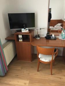 einen Schreibtisch mit einem TV und einem Stuhl in einem Zimmer in der Unterkunft Seminar- und Urlaubshotel Schulz in Bergen