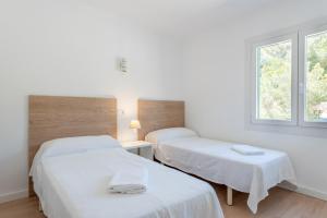 ポルトペトロにあるApartment Sa Caseta 1 by Mallorca House Rentの白い壁の客室で、ベッド2台、窓が備わります。