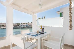 ein weißes Esszimmer mit einem Tisch und Stühlen sowie einem Fenster in der Unterkunft Apartment Sa Caseta 1 by Mallorca House Rent in Portopetro