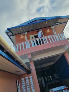 a house with a balcony and a person on the balcony at Trésor Caché TT in Claxton Bay