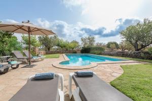 a swimming pool with two chairs and an umbrella at Finca Puig de l'Anar in Manacor