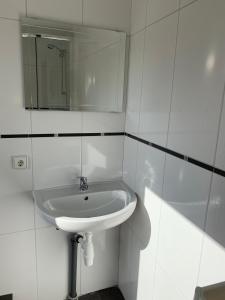 a white bathroom with a sink and a mirror at Ferienhaus für Monteure in Bitterfeld-Wolfen in Steinfurth