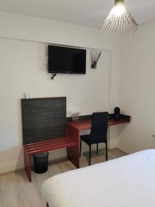 a bedroom with a desk and a television on the wall at Le P'tit Bouchon in Rambervillers