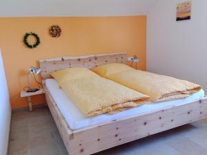 1 dormitorio con 1 cama de madera y 2 almohadas en Haus Sonnentau Wohnung 2, en Kisslegg