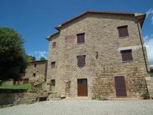 - un grand bâtiment en pierre avec une porte marron dans l'établissement Agriturismo Riposati, à Monticchiello