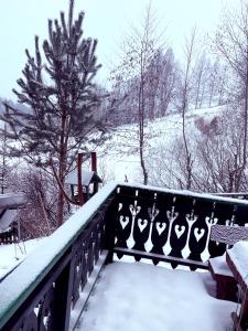 a fence covered in snow with trees and a hill at Pod Salamandrom in Jaworki