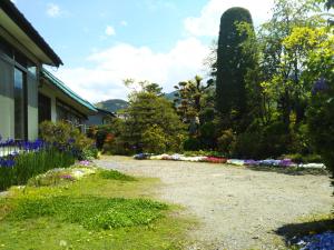 a garden with flowers and trees and a building at ゲストハウス「古民家の宿梨本軒」 in Takayama