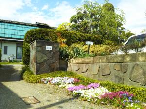 un giardino fiorito accanto a un muro di pietra di ゲストハウス「古民家の宿梨本軒」 a Takayama