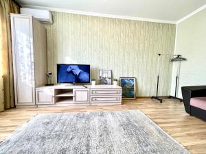 a living room with a flat screen tv on a entertainment center at Cozy three-room apartment with Mountain view in Almaty