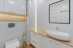 łazienka z białą umywalką i lustrem w obiekcie Comfort Apartments Wilcza w Gdańsku +28 zdjęć