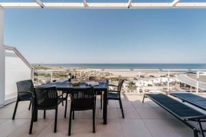 einen Tisch und Stühle auf einem Balkon mit Blick auf den Strand in der Unterkunft Beachfront Atlantic Sunset A07 in Óbidos