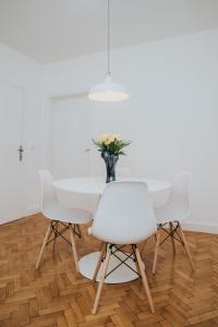 a white dining room with a white table and white chairs at My Home in Arandjelovac