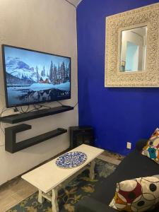 a living room with a tv and a blue wall at Casa colonial en el corazón del Centro Histórico in Mexico City