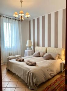 uma grande cama branca num quarto com paredes listradas em IL BALCONE DI AURORA em Verona