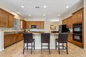 a large kitchen with wooden cabinets and bar stools at Grand Ironhorse in Queen Creek