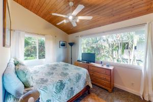 a bedroom with a bed with a ceiling fan and a window at Waipio Glass House in Kukuihaele
