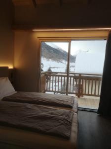 a bedroom with a bed and a large window at Garni Al Silvestri Vei in Livigno