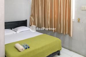 een slaapkamer met een bed met een groene deken bij Aquino Marito Homestay Mitra RedDoorz in Balige