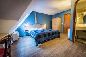 - une chambre dotée d'un lit avec un mur bleu dans l'établissement Hôtel Au Lion, à Ribeauvillé