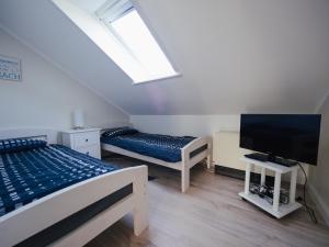 a bedroom with two beds and a flat screen tv at Beachcomber House A in Friedrichskoog