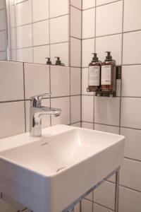 lavabo blanco en el baño con espejo en Danebu Kongsgaard - Boutique Hotel, en Aurdal