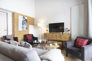 a living room with a couch and chairs and a tv at TERRESENS - Le Hameau de Barthélémy in La Rosière