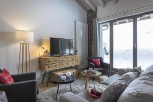 a living room with a couch and a tv at TERRESENS - Le Hameau de Barthélémy in La Rosière