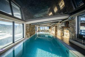 - une grande piscine dans une maison dotée de fenêtres dans l'établissement Resort Sv. František - Hotel Erlebachova Bouda, à Špindlerův Mlýn