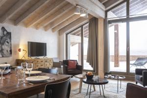 ein Wohnzimmer mit einem Holztisch und Stühlen in der Unterkunft TERRESENS - Le Hameau de Barthélémy in La Rosière