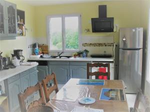 a kitchen with a table and a refrigerator at Le Repos des Crins Noirs in Esson