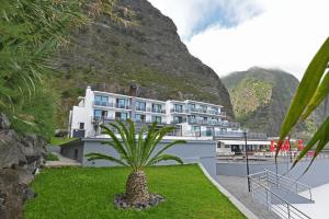 un hotel con una palmera frente a una montaña en Calamar Hotel en São Vicente