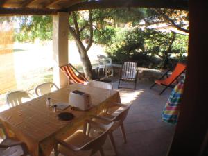 een houten tafel en stoelen op een patio bij Maison de vacances dans un village de vacances à100 m. de la plage in Badesi