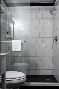 a white tiled bathroom with a toilet and a shower at SoBro Guest House by Black Swan in Nashville