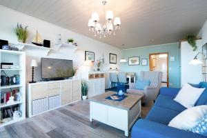 un salon avec un canapé bleu et une télévision dans l'établissement Am Sturmweg 5, Seeschwalbe, à Rosenfelde