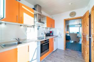 - une cuisine avec des armoires orange et un évier dans l'établissement Am Sturmweg 5, Seeschwalbe, à Rosenfelde