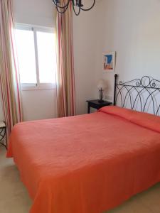1 dormitorio con 1 cama con colcha de color naranja en APARTAMENTO BONITO EN PINAL DEL MAR NERJA, en Nerja
