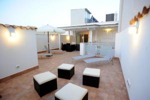 a patio with white chairs and tables and an umbrella at Italiana Resort in Floridia