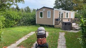 a stroller parked in a yard with a cabin at Renesse Chalet in family friendly area in Renesse