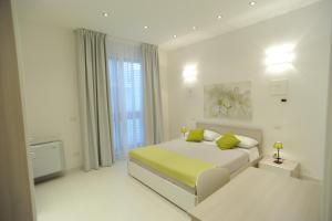 a white bedroom with a bed and a window at Italiana Resort in Floridia