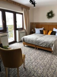 a bedroom with a bed and a chair and windows at Pensjonat Litworówka in Poronin