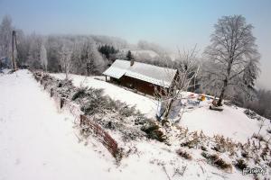 ein Haus auf einem schneebedeckten Hügel mit einem Zaun in der Unterkunft Chata z bali -domek w górach ,,Filipkowy Raj''- Limanowa Nowy Sącz Beskidy Kraków in Rozdziele