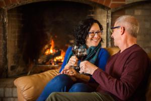 Ein Mann und eine Frau sitzen auf einer Couch mit einem Glas Wein in der Unterkunft The Edenwild Boutique Inn in Lopez