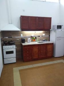 a kitchen with white appliances and wooden cabinets at Casa Tranquila en pasaje , Villa Carlos Paz in Villa Carlos Paz