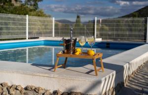einen Tisch mit zwei Weingläsern und Zitronen neben einem Pool in der Unterkunft Alojamiento rural La Granja de Las Monjas in Jaén