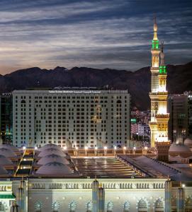 a large building with a clock tower at night at Taiba Suites Madinah in Medina