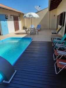 una piscina con sillas y sombrilla en Casa Penha e Beto Carrero, en Penha